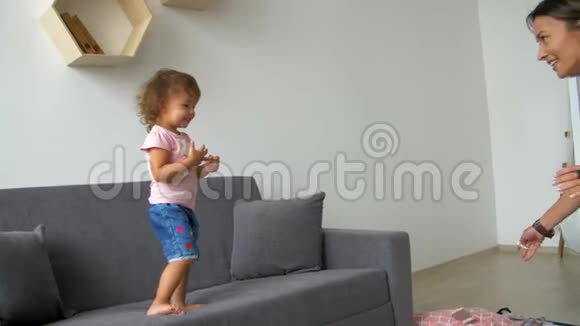 兴奋的年轻母亲和孩子在沙发上玩耍妈妈把婴儿扔到空中视频的预览图