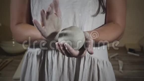 穿着白色围裙的女人用手臂揉着灰色粘土视频的预览图