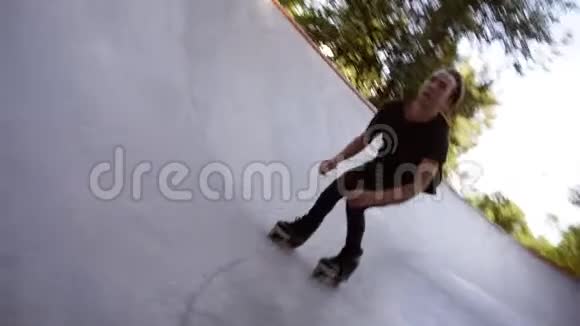 特写镜头一个穿着休闲服的男人正在坡道上的溜冰场里骑着溜冰鞋乘坐滑旱冰视频的预览图