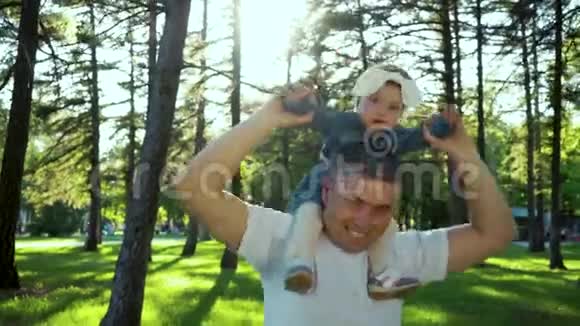 快乐的父亲在阳光明媚的夏日公园里和小女儿肩并肩玩耍视频的预览图