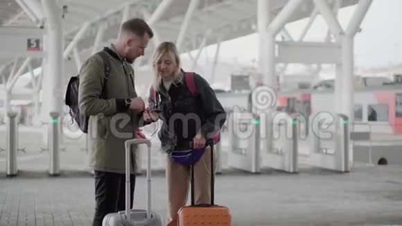 一对夫妇站在机场外面手里拿着滚动的手提箱视频的预览图