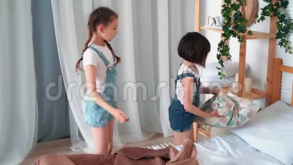 两个小女孩铺床放枕头用毯子盖慢动作视频的预览图