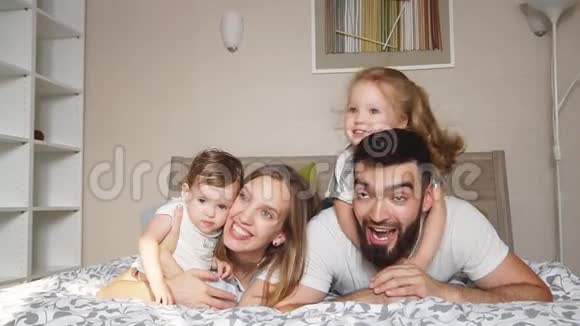 幸福快乐友好的家庭躺在床上视频的预览图