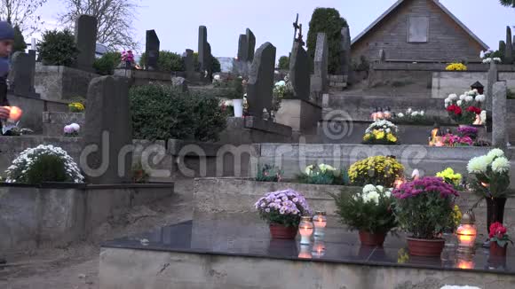 悲伤的人在墓地的黑色大理石墓碑上放了两支蜡烛4K视频的预览图