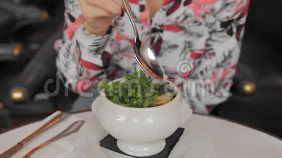 未被认出的法国女人穿着五颜六色的衬衫用勺子吃传统的法国洋葱汤慢动作特写视频的预览图