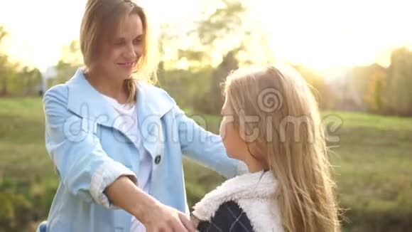 可爱的女人和她成年的十几岁的女儿互相拥抱站在秋天公园的中间户外肖像画视频的预览图