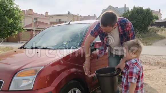 爸爸洗了他那辆漂亮的红色汽车的挡风玻璃让他的小儿子慢慢地走视频的预览图