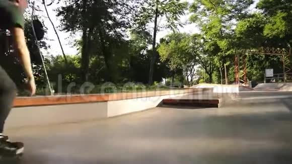 一个年轻的溜冰者滑在一个木栏杆上的摩登滑板公园与坡道追逐镜头阳光明媚视频的预览图