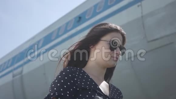 肖像年轻自信的黑发女孩戴着太阳镜站在大飞机前夏天旅行的乐趣视频的预览图