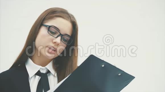 这位商务女士站在白色的背景上同时拿着一个黑色的文件夹里面的文件拥抱着她视频的预览图