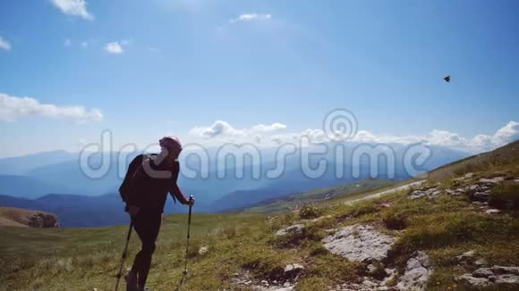年轻女子带着背包和徒步旅行杆走上山顶慢动作女士在美丽的地方徒步旅行视频的预览图