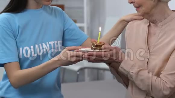 年轻志愿者和老年女性庆祝生日退休人员吹蜡烛视频的预览图
