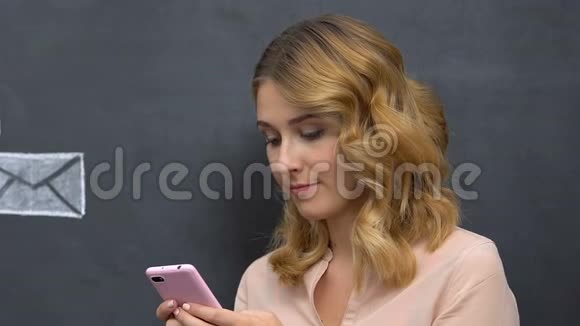 年轻漂亮的女孩拿着智能手机对着镜头微笑社交媒体图标视频的预览图