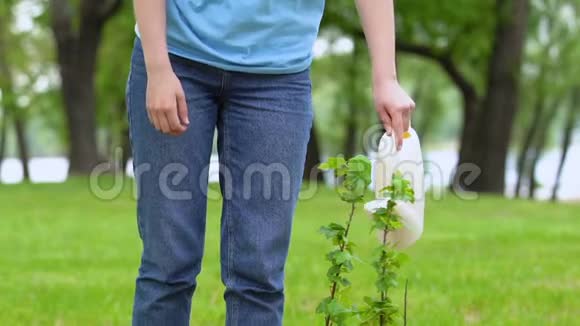 微笑女性志愿者用罐头浇灌树苗拯救自然的理念视频的预览图