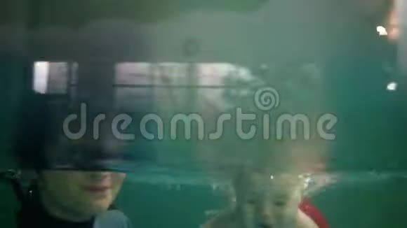 妈妈和她的宝宝穿着可爱的红色短裤在室内游泳池里玩得很开心一起潜水视频的预览图