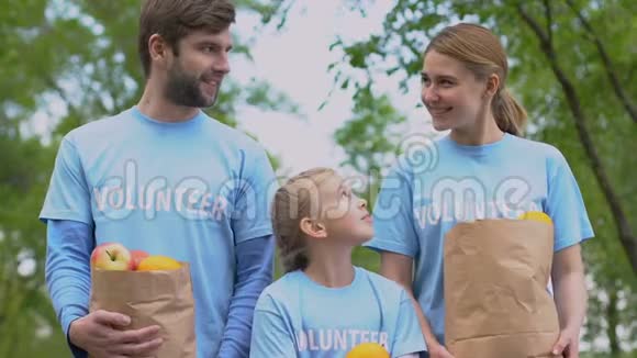 快乐的志愿者家庭带着苹果纸袋微笑的相机慈善机构视频的预览图