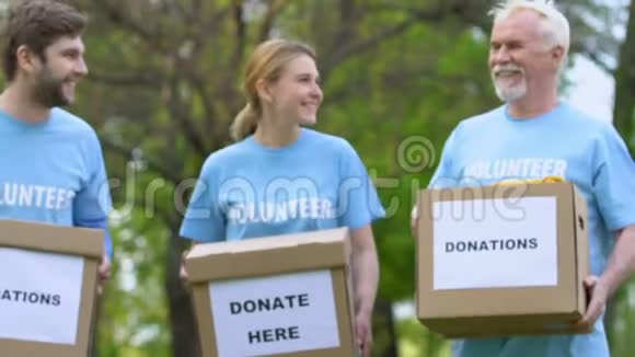 老年和青年志愿者带着捐款箱在公园散步充满人性和帮助视频的预览图