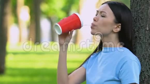 女孩在塑料杯里喝鸡尾酒在草地上扔垃圾乱扔垃圾视频的预览图
