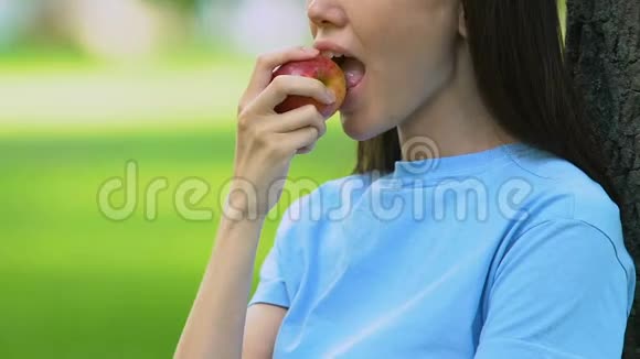 美丽的女人在户外吃甜苹果健康的零食维生素营养视频的预览图