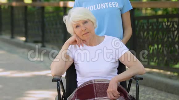 志愿者带着沮丧的坐在轮椅上看镜头的老年妇女医院公园视频的预览图