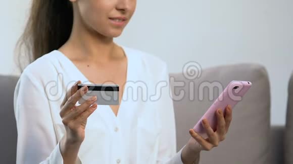快乐女性在手机上插入信用卡号码购物申请视频的预览图