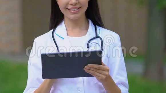 微笑医生在平板电脑上使用应用程序进行在线咨询特写视频的预览图