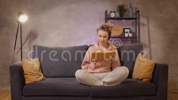 一个年轻的女人坐在沙发上看书那个人送给他的爱人一份礼物视频的预览图