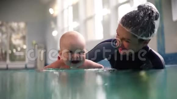 妈妈穿着泳衣抱着儿子她在游泳池里玩得很开心健康生活方式的概念视频的预览图