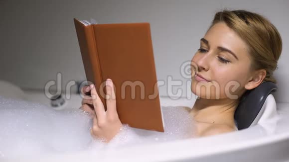 带泡沫泡浴的女性轻松看书晚上在家特写视频的预览图