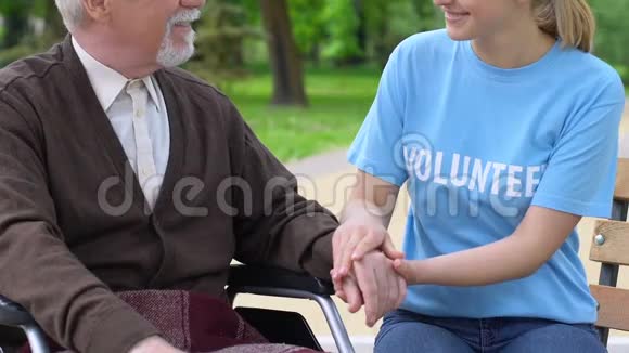 微笑青年志愿者支持公园中的老年残疾人帮助退休人员视频的预览图