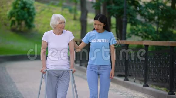 女志愿者支持生病的老妇人步行架康复困难视频的预览图