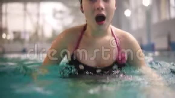 戴着游泳帽的女孩在水面上吸起空气潜入水中少女在水下潜水录像视频的预览图