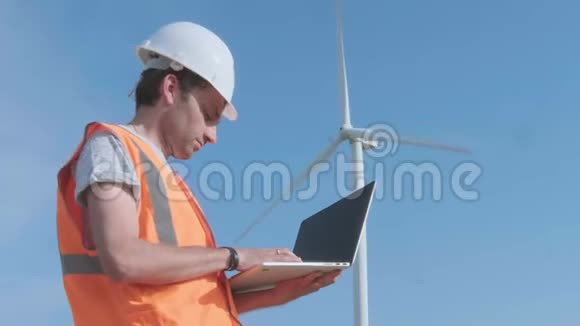 当技术人员操作笔记本电脑时风力涡轮机正在旋转清洁环保的能源理念男性视频的预览图