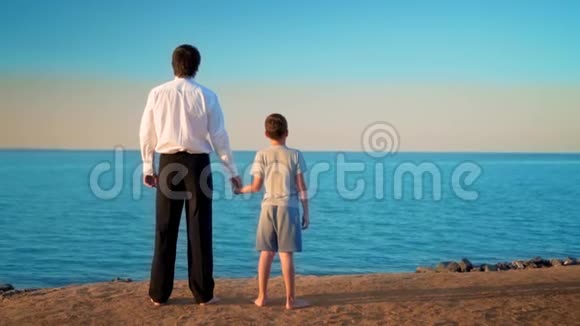 父亲和儿子站在海边的手边视频的预览图