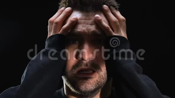 恐惧的男人在黑暗的背景下抱着头心理疾病特写视频的预览图
