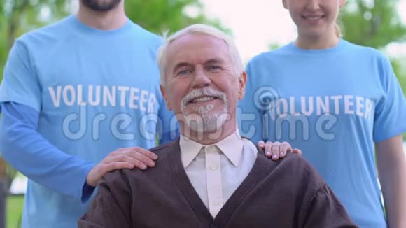 微笑志愿者站在老残疾人背后社会支持慈善视频的预览图