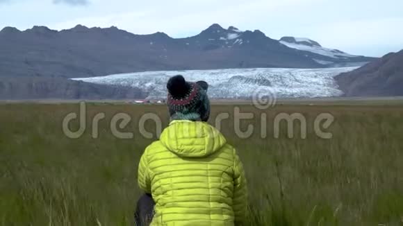 一个女人坐在草地上享受冰岛美丽的自然视频的预览图