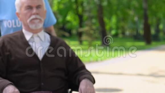 女志愿者与孤独的残疾人轮椅男子在公园散步支持视频的预览图