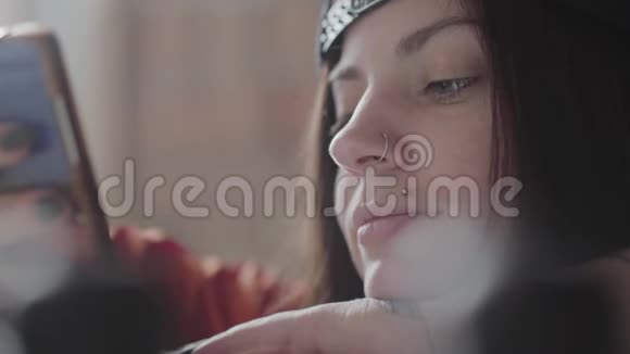 一个年轻女子的脸紧闭嘴唇穿孔鼻子里有戒指在手机上发短信漂亮的女孩视频的预览图