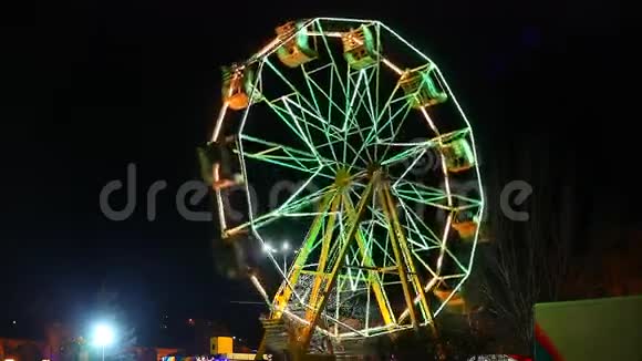 旋转木马一个垂直摩天轮在夜间旋转并发出绿色和黄色的灯光视频的预览图