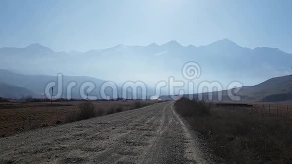 乡村碎石路朦胧中的山景全景晨秋山水在高加索山脉视频的预览图