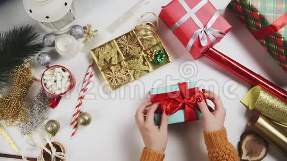 两位女士包装圣诞礼物白色桌子背景上的礼物和节日装饰品视频的预览图