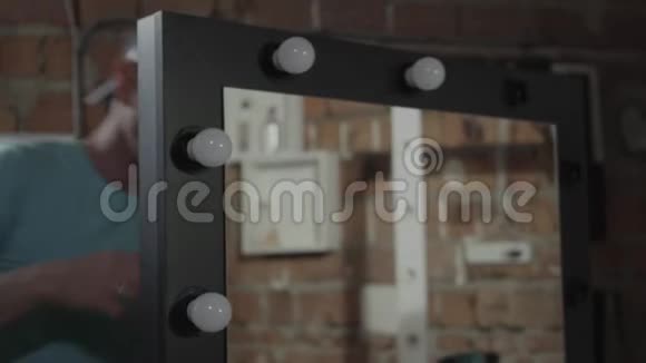 关闭电工在镜子里拧灯泡手制造的概念家具生产视频的预览图