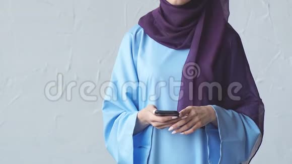 年轻的穆斯林妇女拿着智能手机看着摄像机视频的预览图