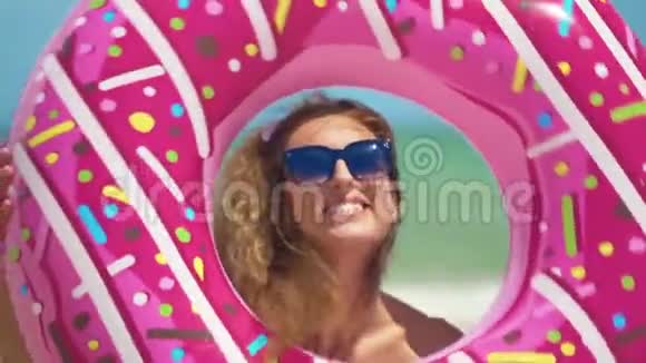 美丽的女孩与充气甜甜圈在海上跳舞特写镜头视频的预览图