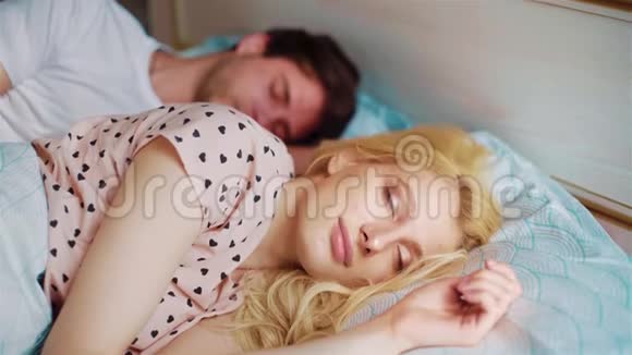 年轻夫妇早上在床上拥抱女人睁开眼睛视频的预览图