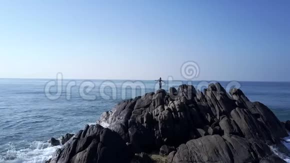 女士的剪影在海洋的灰色岩石悬崖顶部冥想视频的预览图