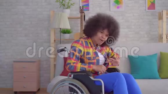 非洲女性博客写手在相机关闭前在轮椅上用非洲发型致残视频的预览图