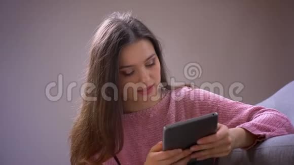 特写镜头年轻漂亮的黑发白种人女性在平板电脑上开心地笑着看着镜头视频的预览图