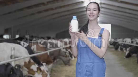 年轻漂亮的女农民带着奶牛在农场里微笑着展示优质的认证牛奶视频的预览图